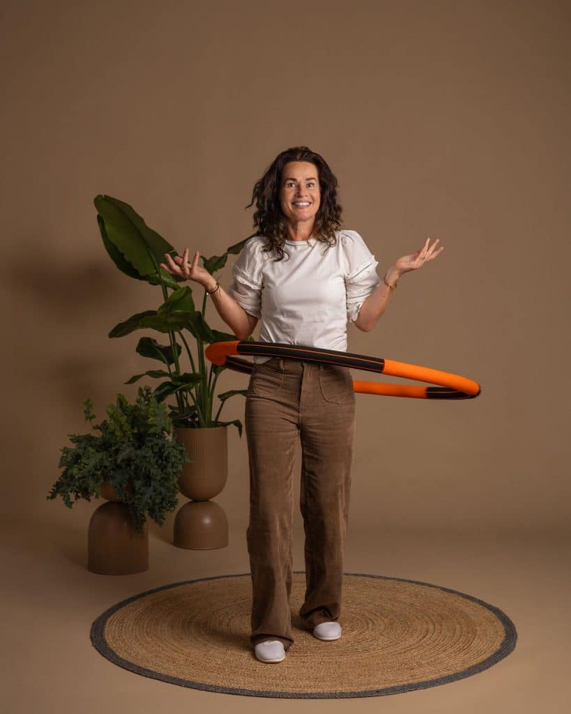Angelique staat glimlachend met een oranje Bodyhoop om haar middel.